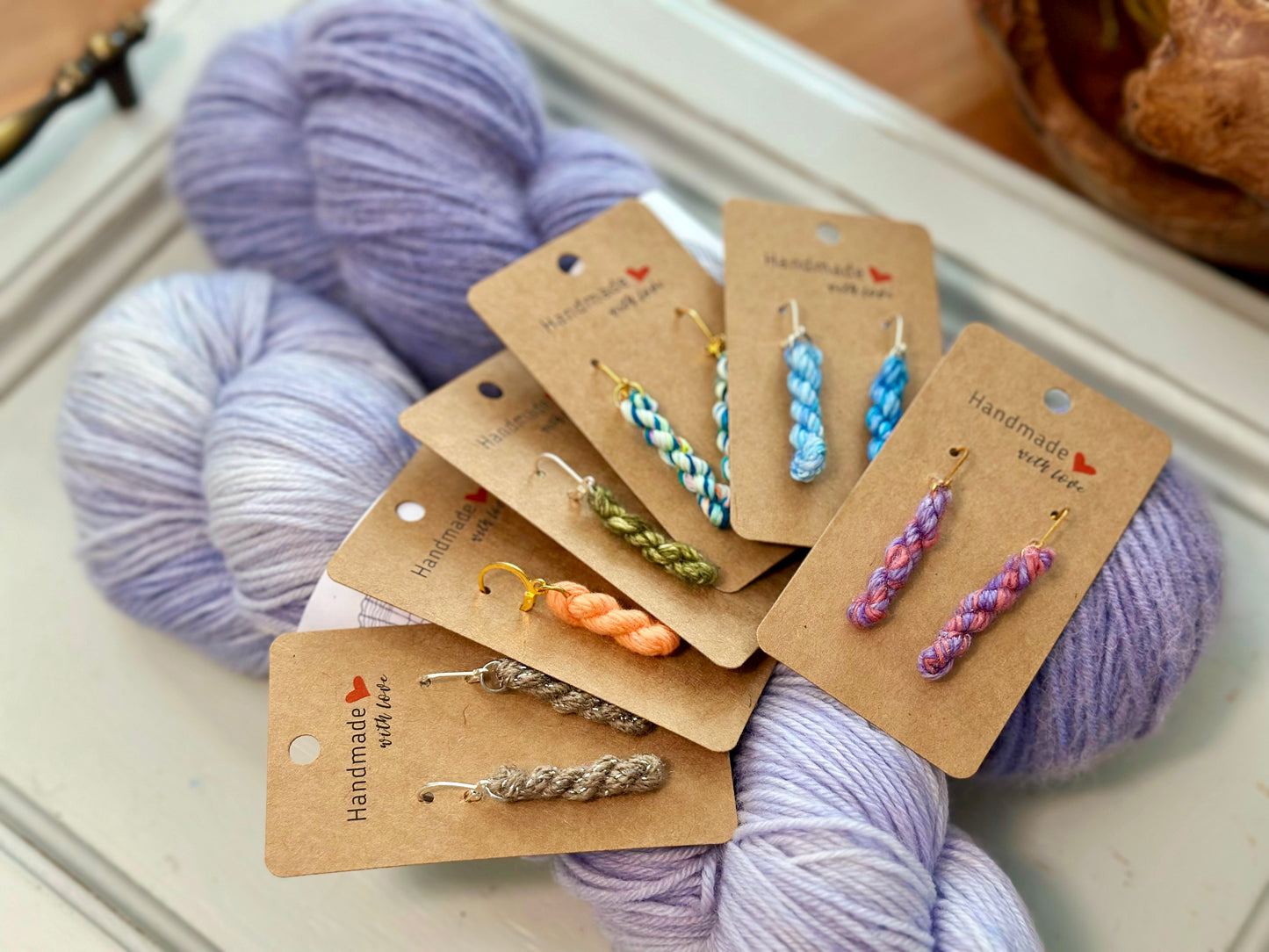 lavender yarn skeins with mini yarn skein earrings of many colors on earring card holders fanned out to